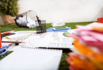 heap of business objects and office supplies laying on green grass carpet at office, business